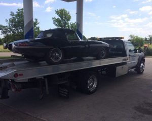 A flatbed truck is towing a car, showcasing the vehicle securely positioned on the truck's platform.