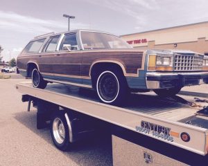 A brown and white car is loaded onto a flatbed truck, ready for transport.