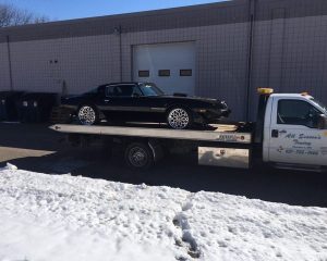 A flatbed truck transporting a car on its rear, showcasing the vehicle secured for transport.