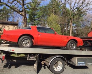 A red car is loaded onto a flatbed truck, ready for transport.