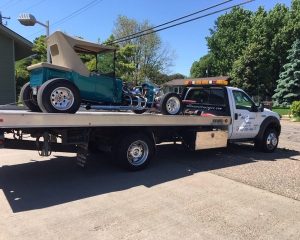 A tow truck transporting a car on its flatbed, showcasing the vehicle secured for transport.