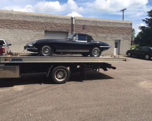 A classic car is securely loaded onto a flatbed truck for transportation.