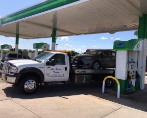 A tow truck is parked at a gas station, ready to assist vehicles in need of towing services.