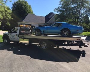 A blue car is being transported on a flatbed tow truck, showcasing its secure placement for safe transport.