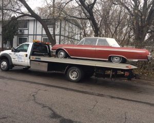 A tow truck transporting a red car on its flatbed, showcasing the vehicle's secure placement for safe transport.