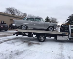 A tow truck transporting a vintage car, showcasing the classic vehicle secured on its flatbed.